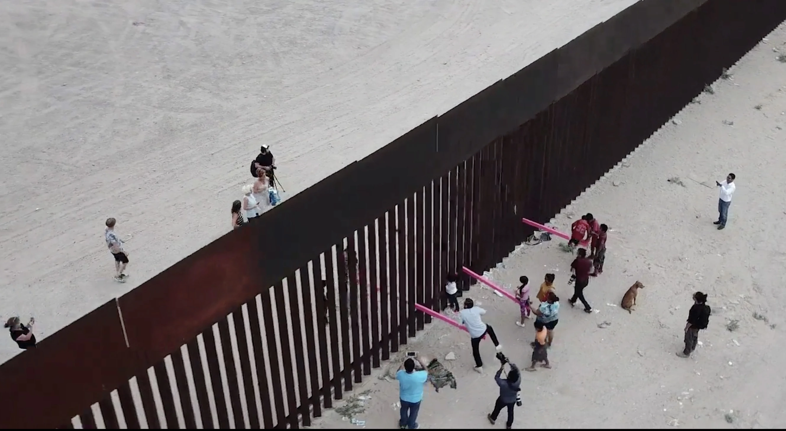 Teeter-Totter Wall consists of three bright pink teeter-totters, which were slotted into gaps in the steel boundary wall by designers from both sides of the border