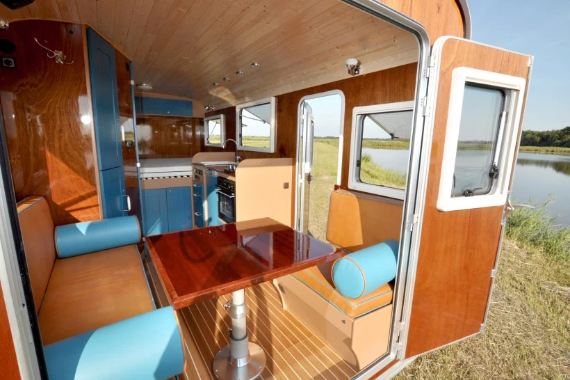 The interior includes a kitchen area, bathroom, dining area and bedding