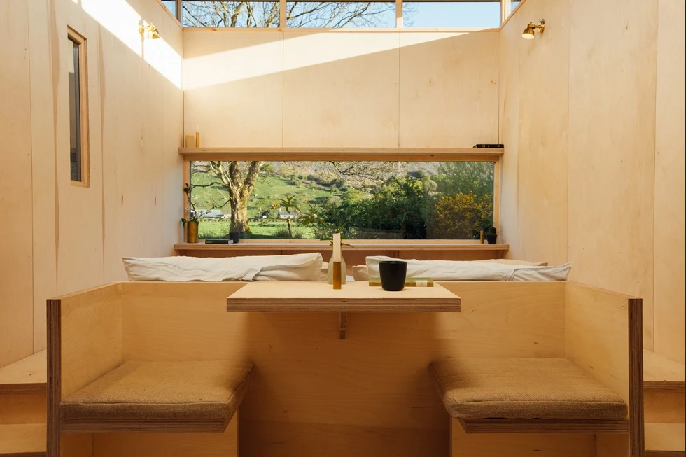 A kitchen and built-in table form a sitting space, while the bed sits on a raised platform