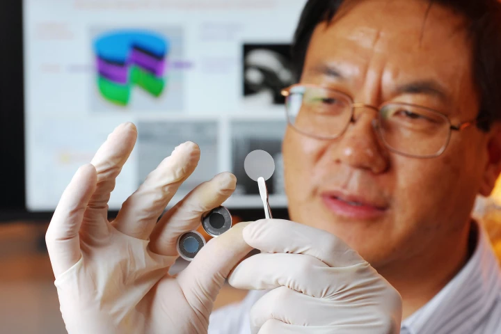Georgia Tech researcher Zhong Lin Wang holds the components of a new self-charging power cell that uses piezoelectric materials to directly convert mechanical energy to chemical energy (Georgia Tech Photo: Gary Meek)