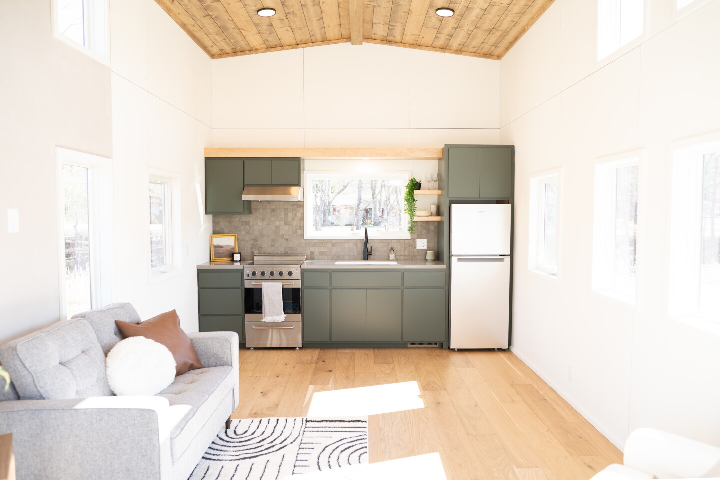 The Pisgah Park Model's living area includes a kitchen with a fridge/freezer, an oven with radiant electric cooktop, a built-in dishwasher, and cabinetry space