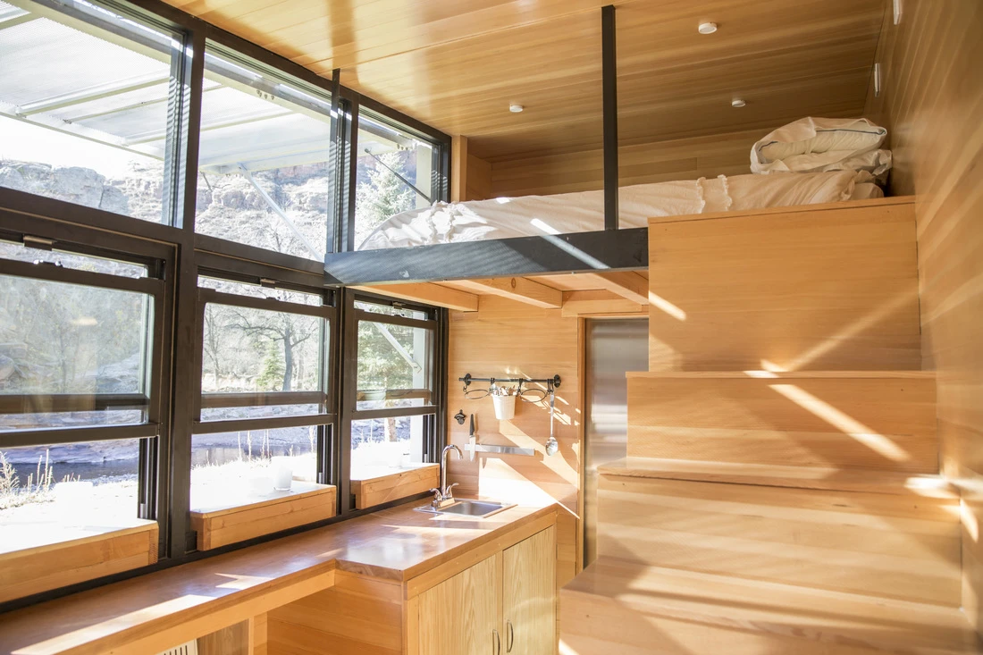 The interior is split between a snug primary living space on the ground floor, and a small loft area with queen-sized bed