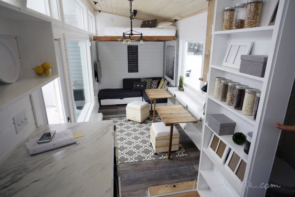 The Open Concept Rustic Modern Tiny House's storage unit can be used as two separate desks, one large desk, or a dining table