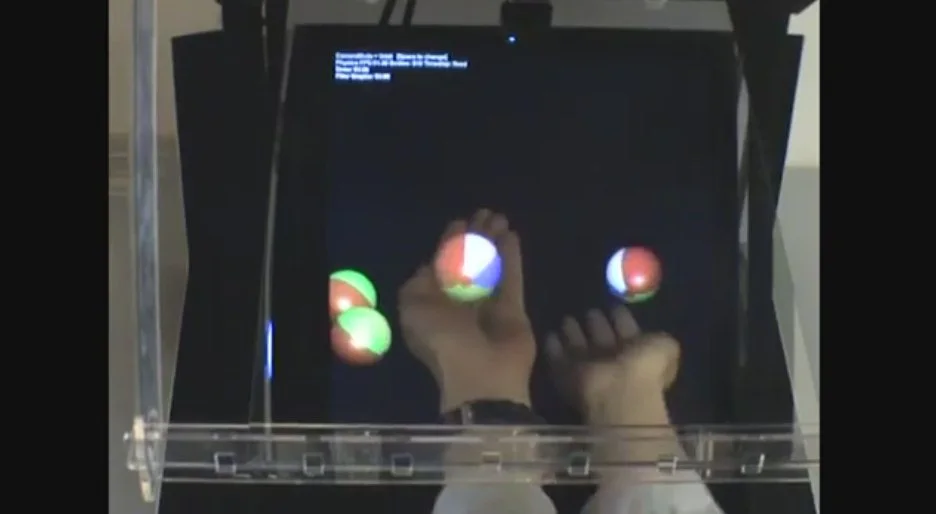 The HoloDesk system uses Microsoft's Kinect camera, an overhead screen that projects a 2D image through a half-silvered beam splitter into a viewing area beneath, face-tracking software and custom algorithms to bring everything together in real time