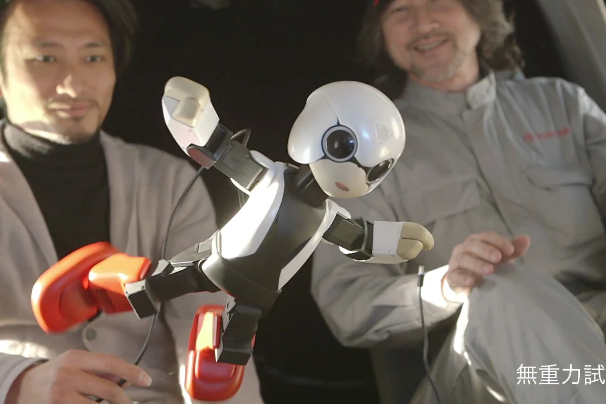 Kibo the Japanese communication robot floats in zero gravity aboard an airplane with its creator, Tomotaka Takahashi (left background)