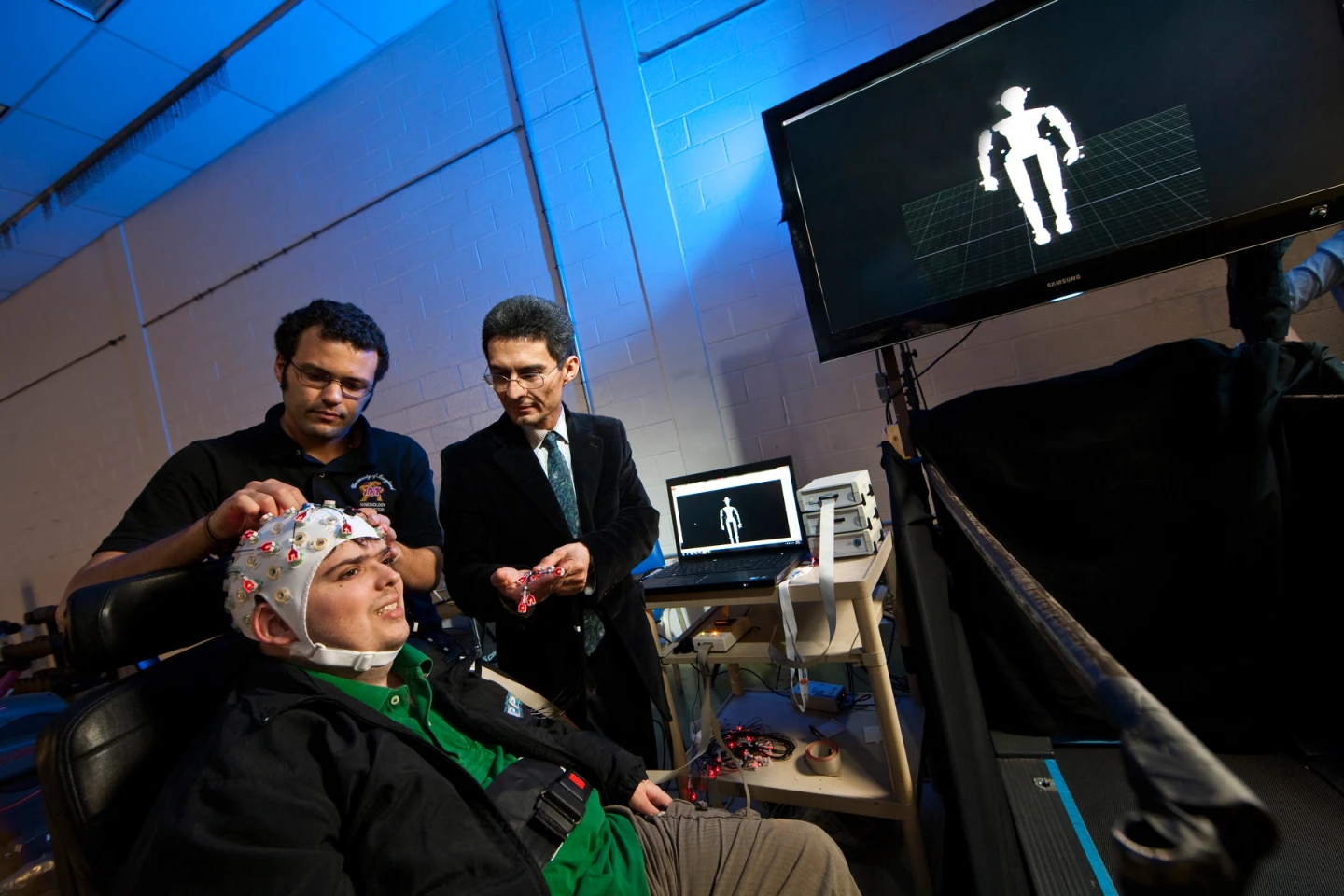 Alessandro Presacco, a graduate researcher in UMD's Neural Engineering and Smart Prosthetics Lab, adjusts a version of Brain Cap headset worn by Steve Graff, while JosÃ© 'Pepe' Contreras-Vidal looks on (Image: University of Maryland)