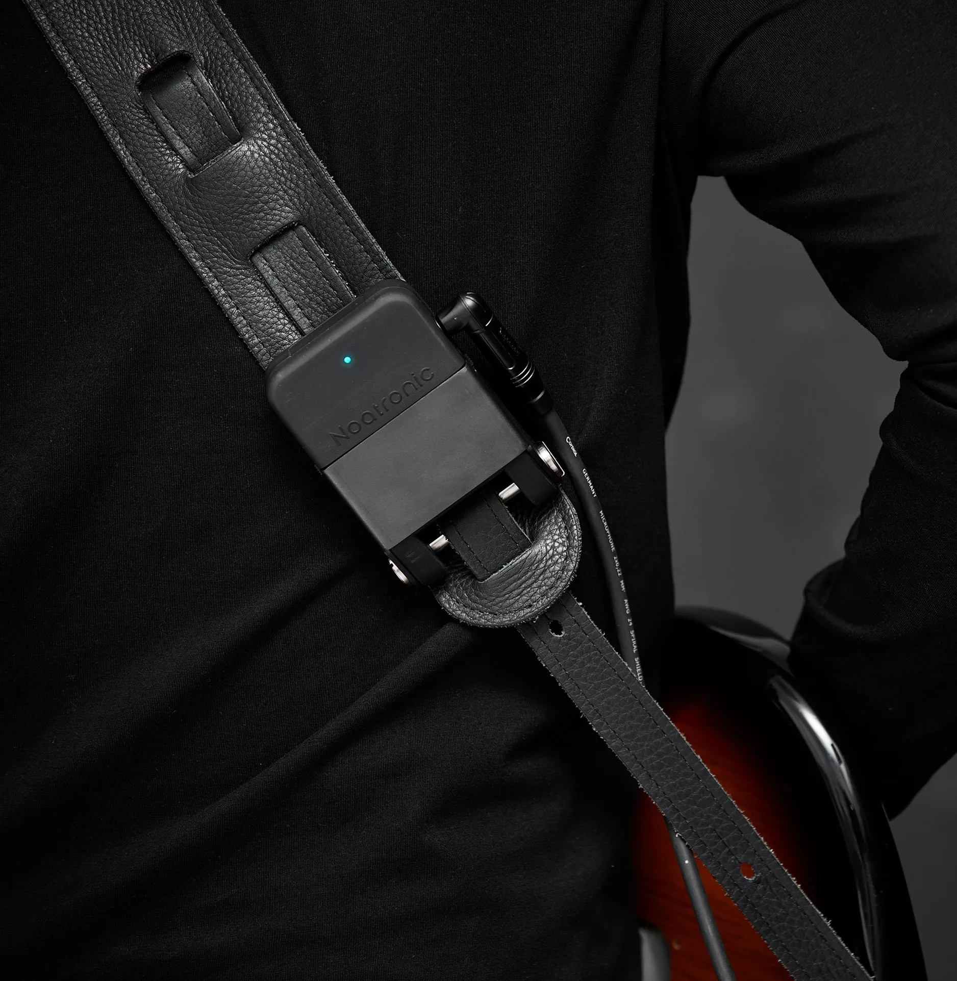 The battery-powered transmitter unit is mounted to a guitar strap