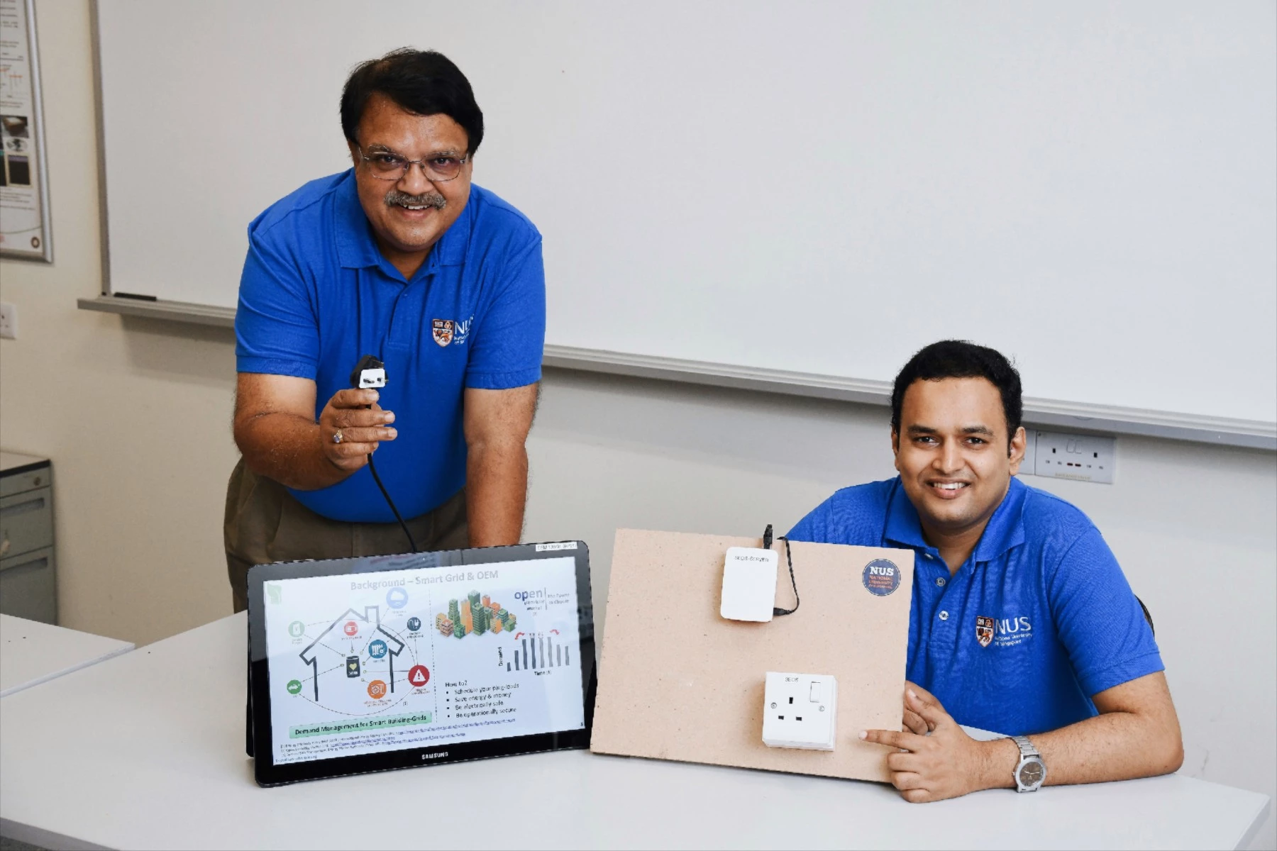 Assoc. Prof. Sanjib Kumar Panda (left) and Dr. Krishnanand Kaippilly Radhakrishnan with a prototype of the Smart Electrical Outlet/Socket (SEOS) system