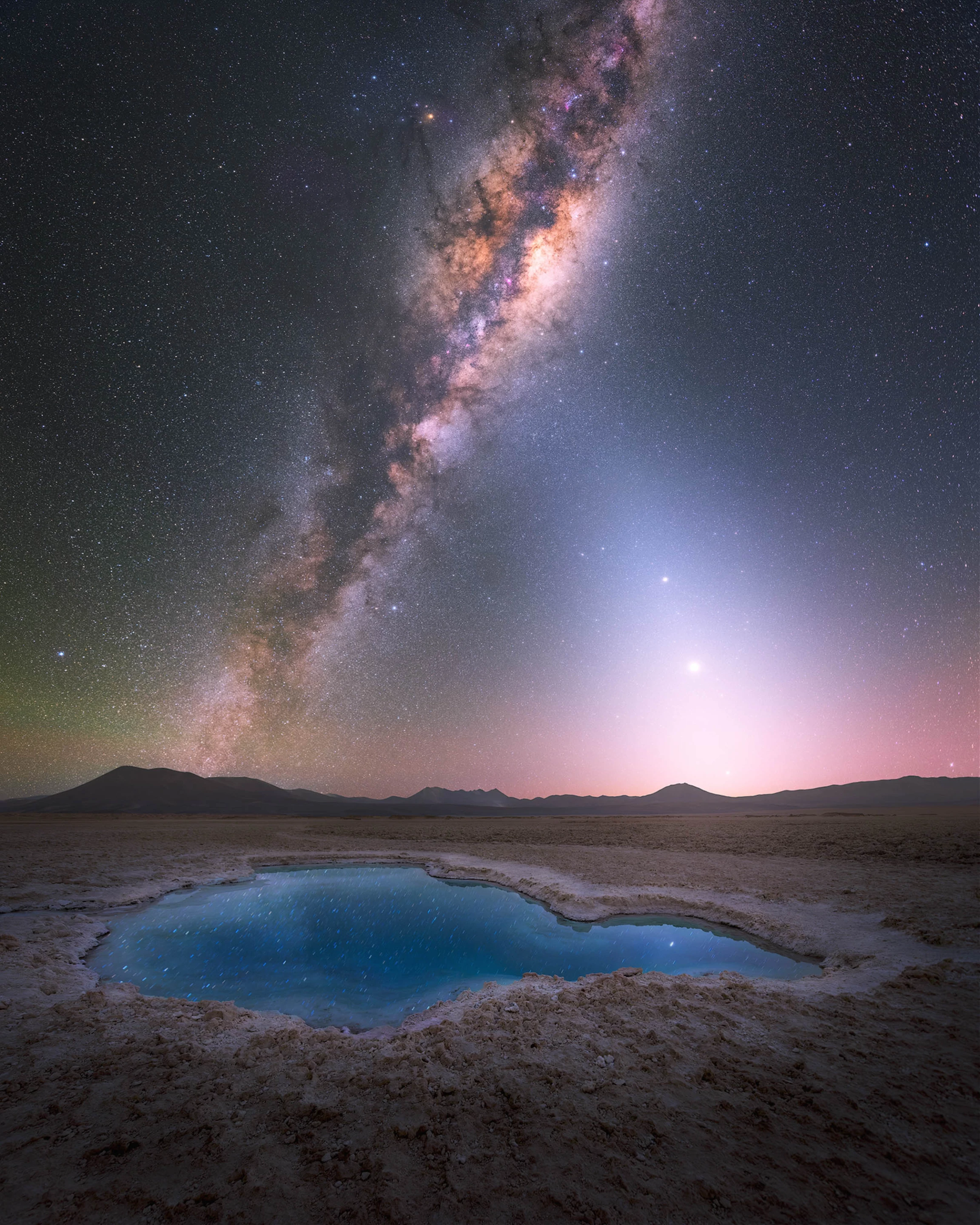 Blue Lagoon Under the Stars by Yuri Beletsky, taken in Chile. This inviting lagoon in the Atacama Desert mirrors the Milky Way and the Zodiacal light (to the right), the sky glow coming from sunlight reflecting off dust throughout the solar system