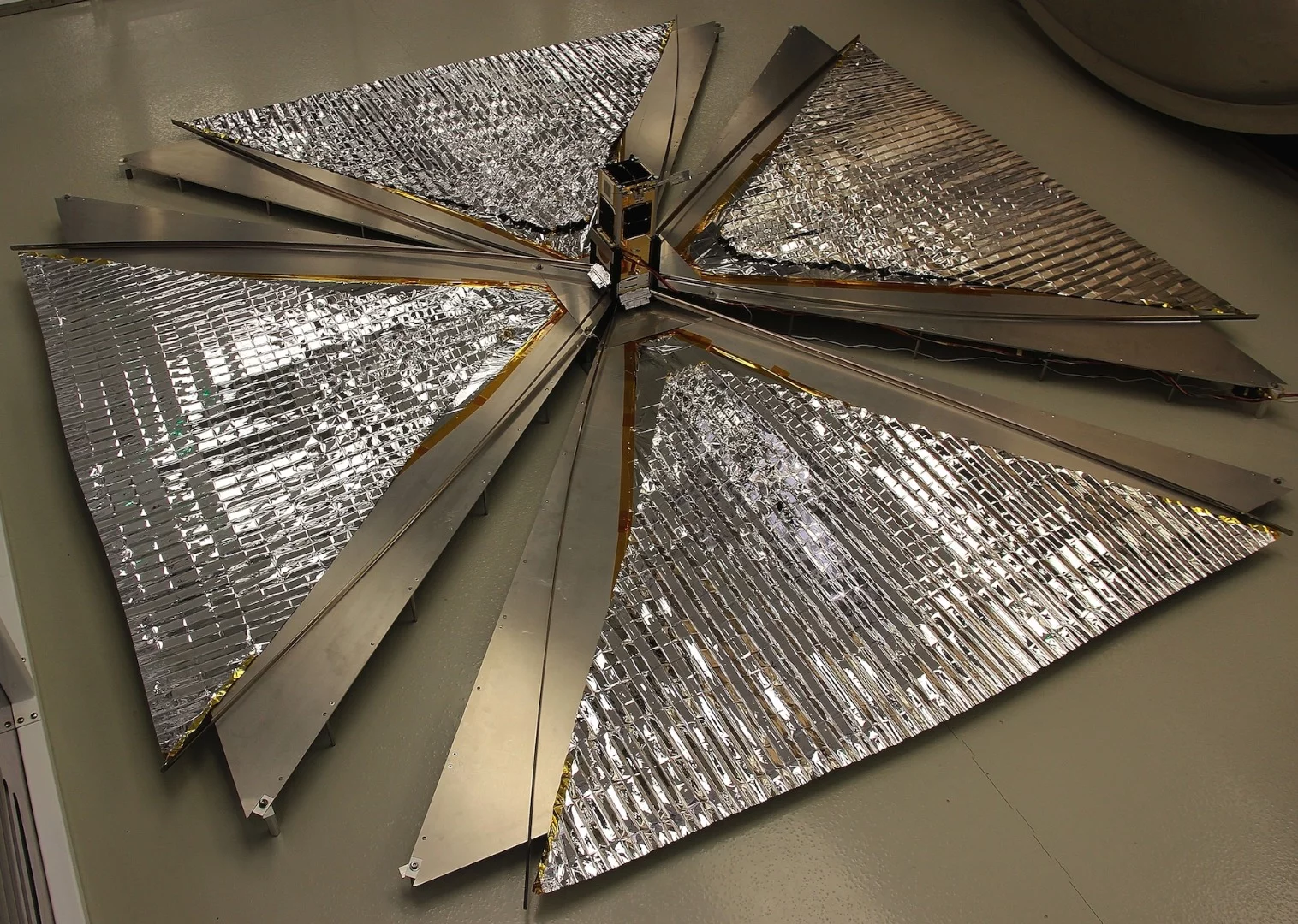 The CanX-7 satellite with its 1 square-meter (10.78 sq ft) drag sails unfurled, in a test before launch