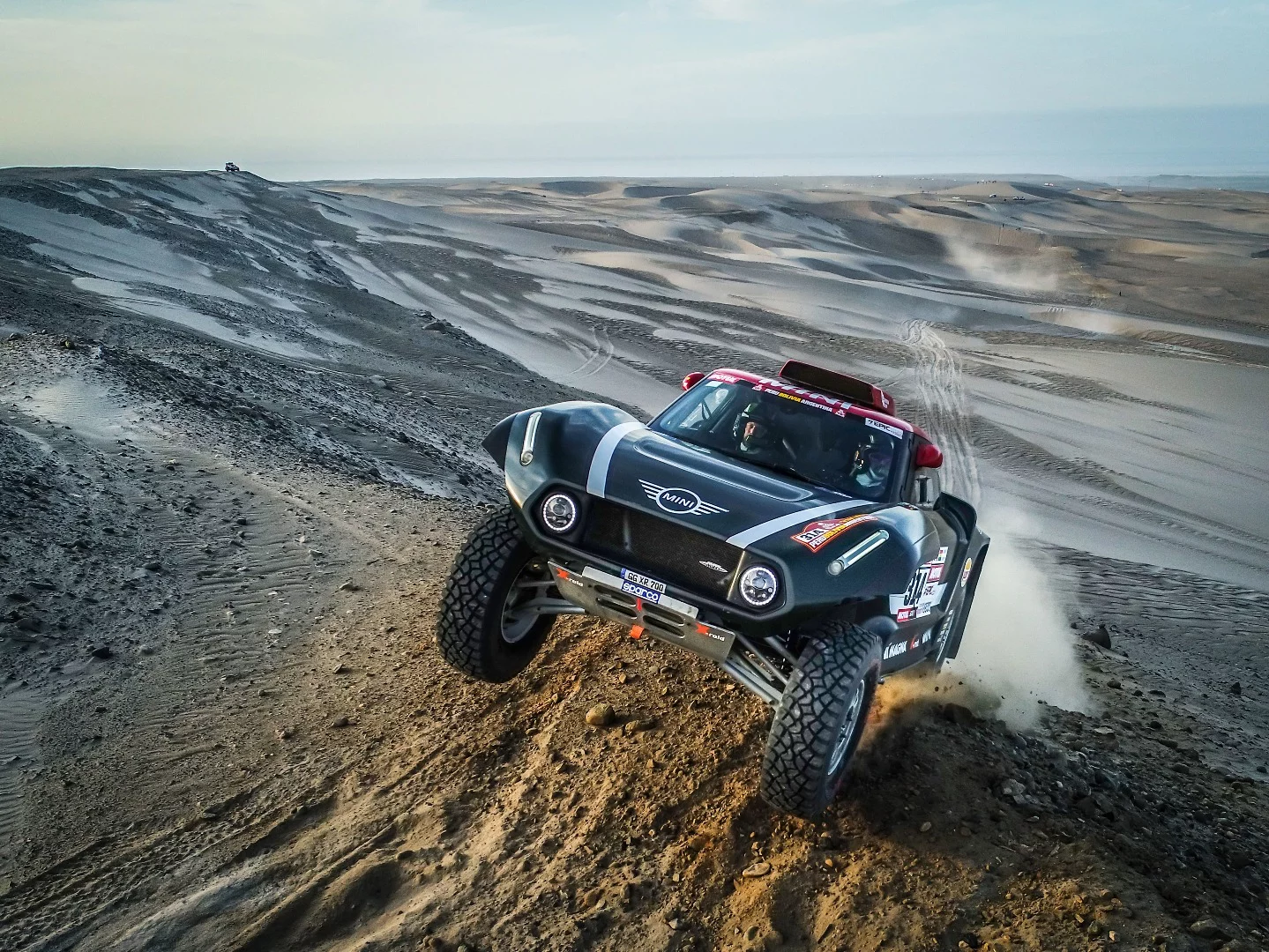 A frighteningly close wide-angle portrait of Al-Rajhi and Gottschalk's Mini cresting a hill; Dakar photography is not for the timid