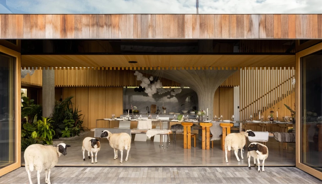 A wall of folding glass windows frames the dining zone