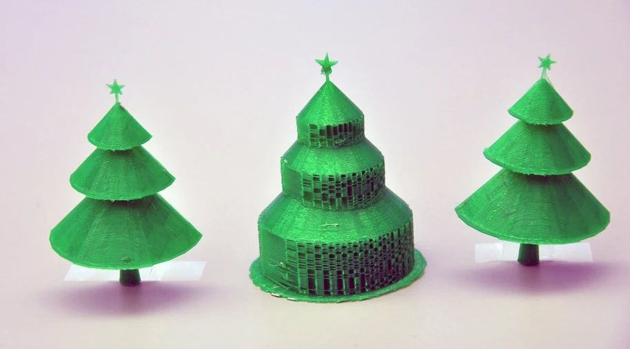 The Christmas tree in the center was 3D-printed in the traditional manner, and displays the extra material to support each branch. Beside it are the two halves of the same tree printed using the new algorithm, with no supportive material to remove (Photo: Simon Fraser University)