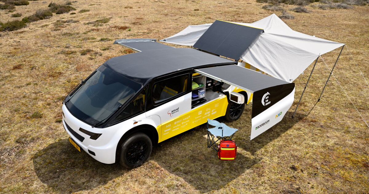 A teardrop-shaped solar-paneled vehicle with medical equipment visible through side windows, parked on unpaved ground.