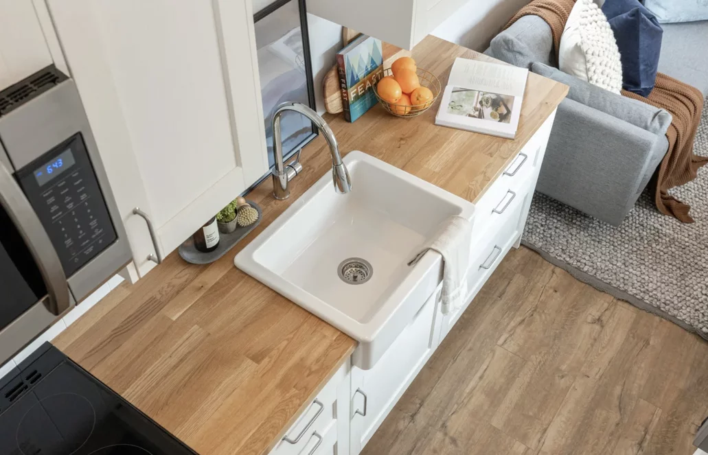 The Loft Ruby Edition's kitchen includes a farmhouse-style sink, a microwave, propane-powered three-burner stove, an oven, and quite a lot of cabinetry