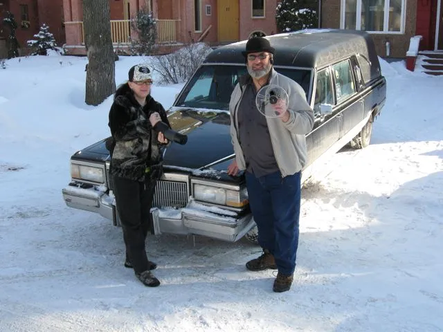 Paranormal investigators Rona Anderson and Ben Myckan sporting some of their ghost-hunting gear in front of their hearse, Nocturna