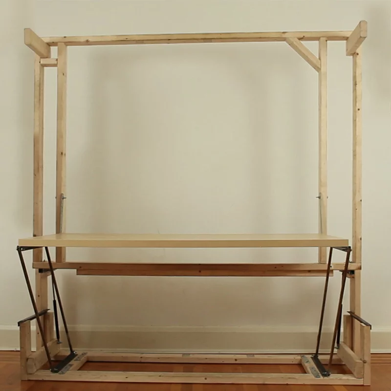The wooden frame rests against a wall, lifting up the full-size desk in the process