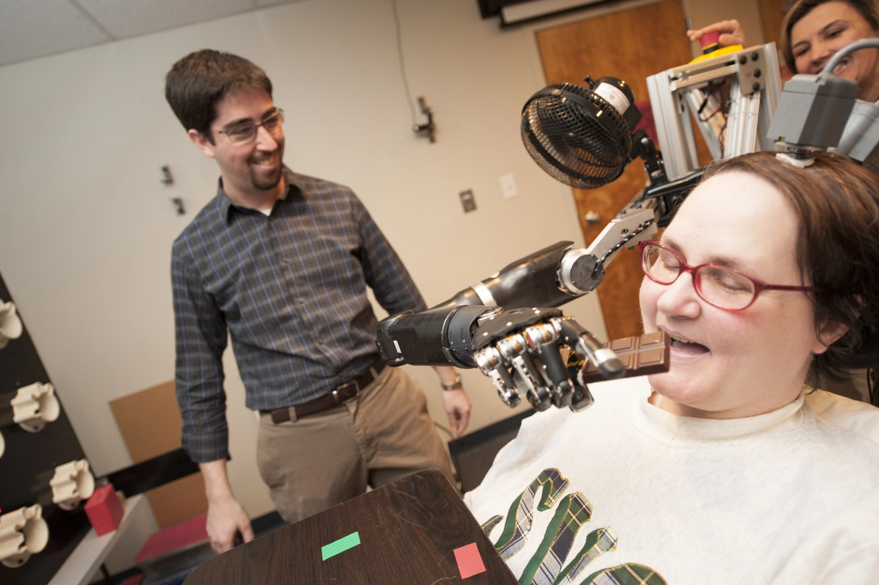 Jan Scheuermann, who has quadriplegia, takes a bite out of a chocolate bar she has guided into her mouth with a thought-controlled robot arm (Photo: UPMC)