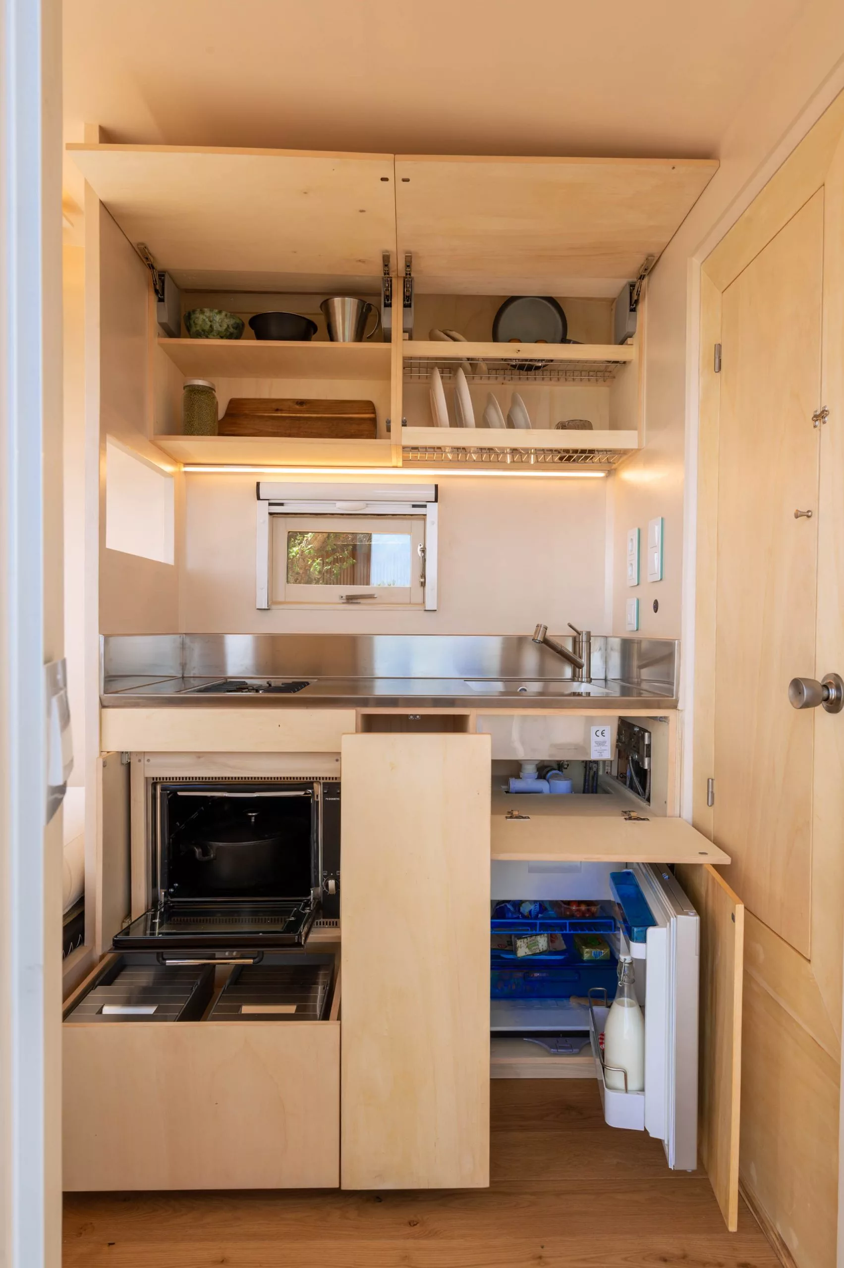 The Freeland Tiny House's kitchen includes a small fridge, oven, a two-burner propane-powered stove and a sink
