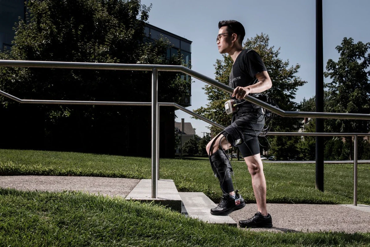 A battery pack and actuators are worn at the hip, with cables fed down to a fabric sleeve wrapped around the weakened leg that provides gait assistance