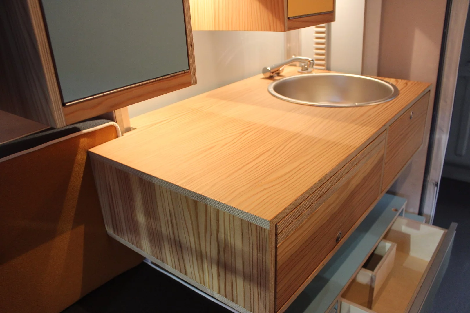 The basic kitchen area with sink and countertop – the portable single-burner stove is stored in a drawer below the counter, the fridge on a slide-out below the bench on the opposite side