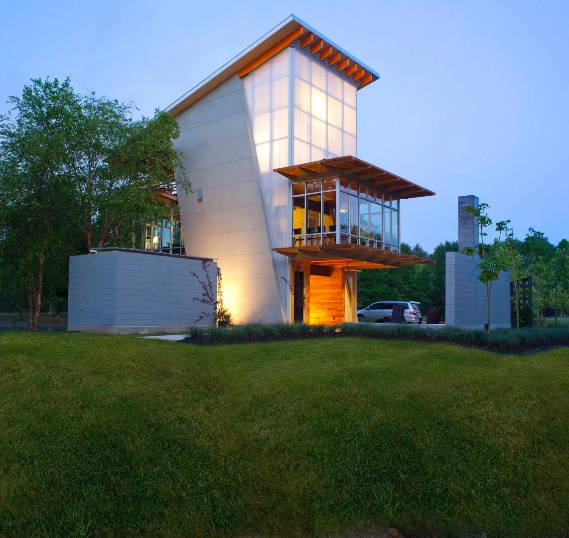 The sloping roof serves both aesthetic and practical purposes, channeling rainwater runoff into the pond and ensuring that maximum sunlight reaches the roof-based solar array