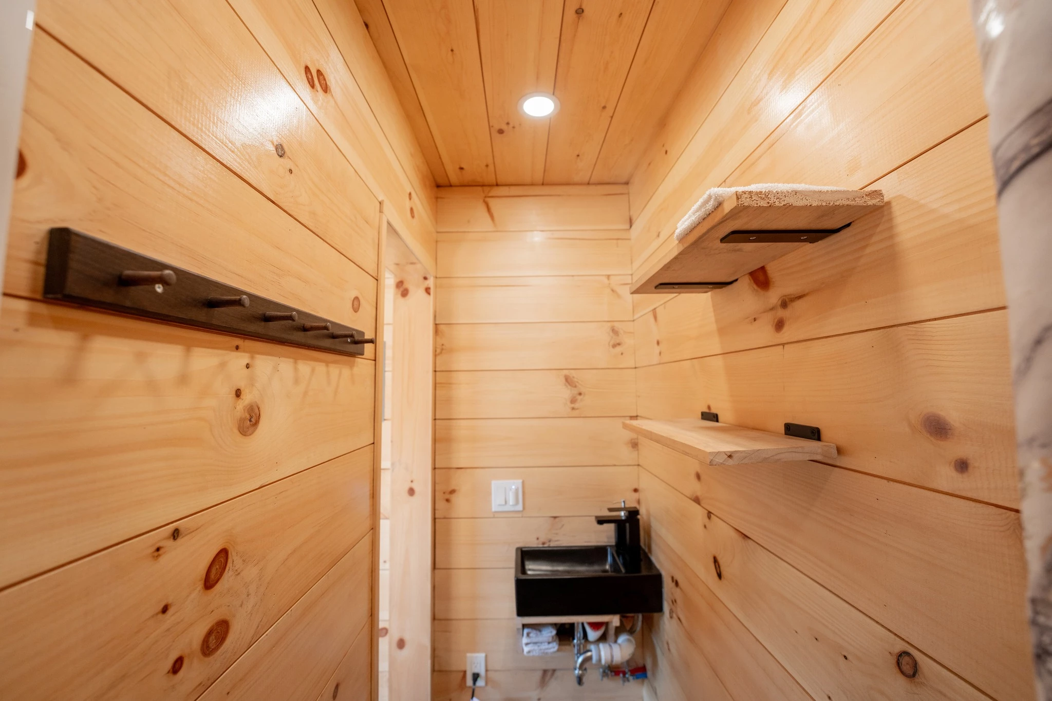 The tiny house sauna includes a small bathroom with a shower and sink, though this model has no toilet