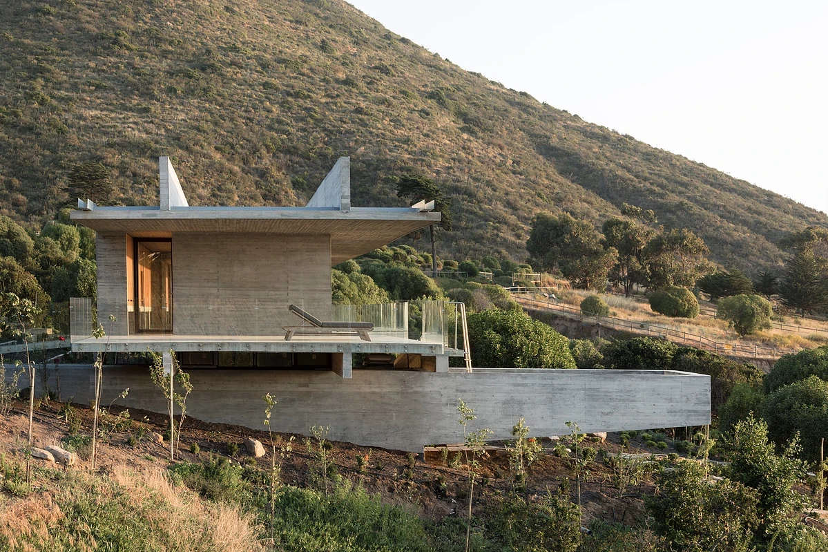 The pool at La Casa H can be accessed via the upper balcony and is housed inside a cantilevered concrete wedge that runs beneath the upper story and presents a sunken entranceway on the other side