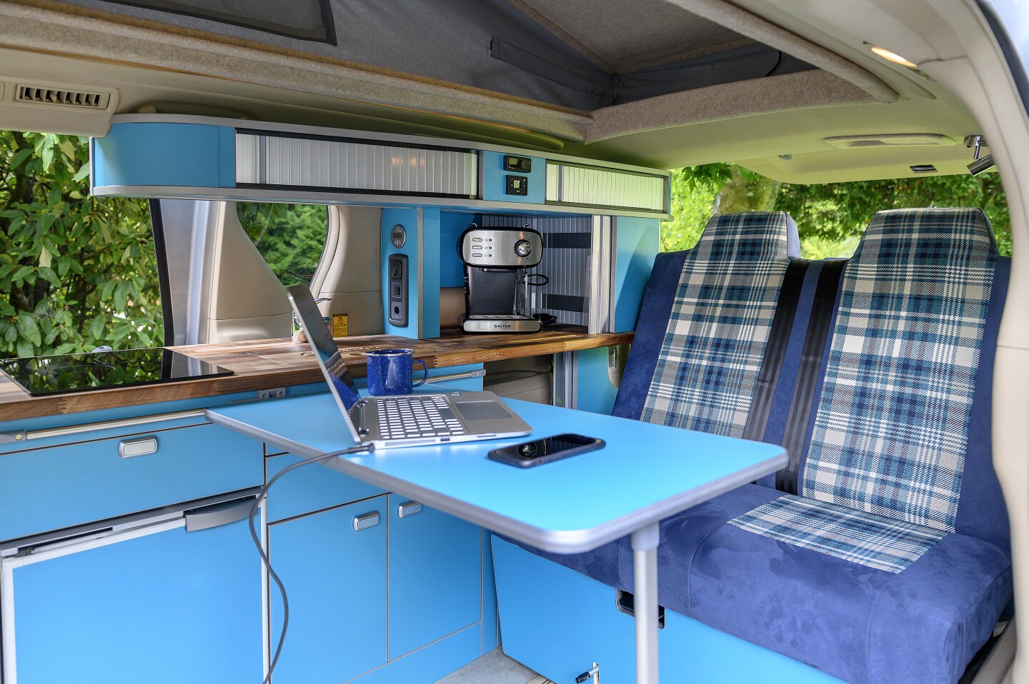 The table breaks down and straps to the tailgate during travel, and sets up in the middle of the van to serve as a dining area or workstation