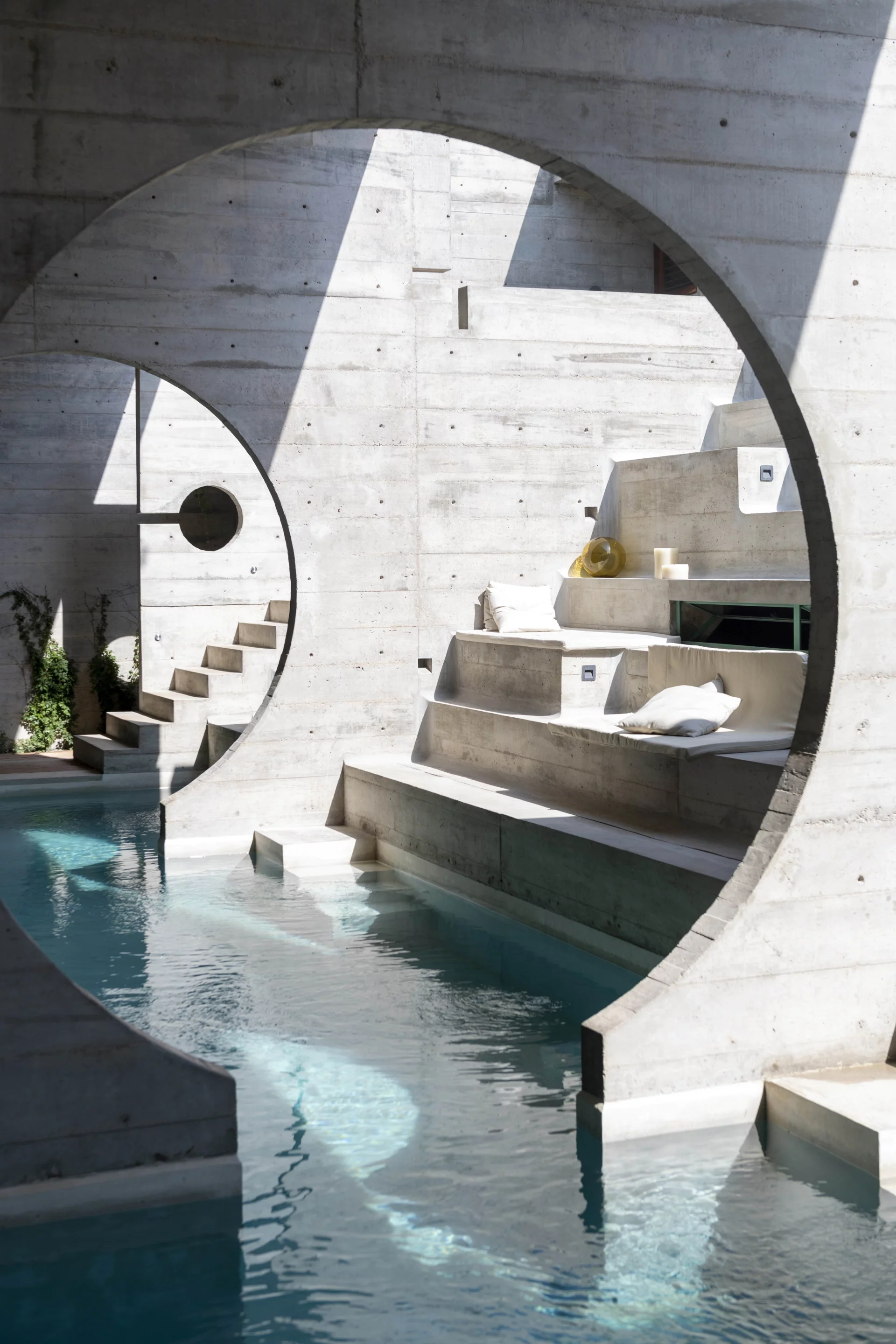 Circular cut-out concrete walls interact with the hotel's infinity pool