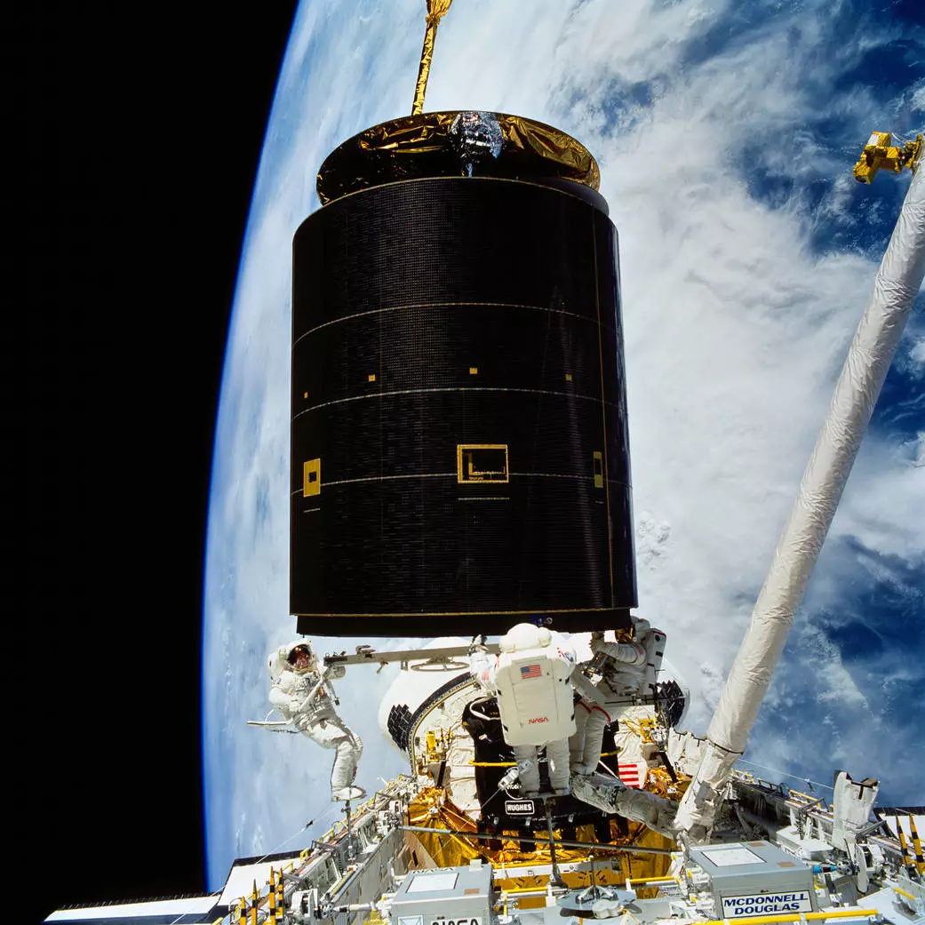 Three astronauts move the Intelsat VI satellite into the cargo bay of the Endeavour Space shuttle on May 13, 1992