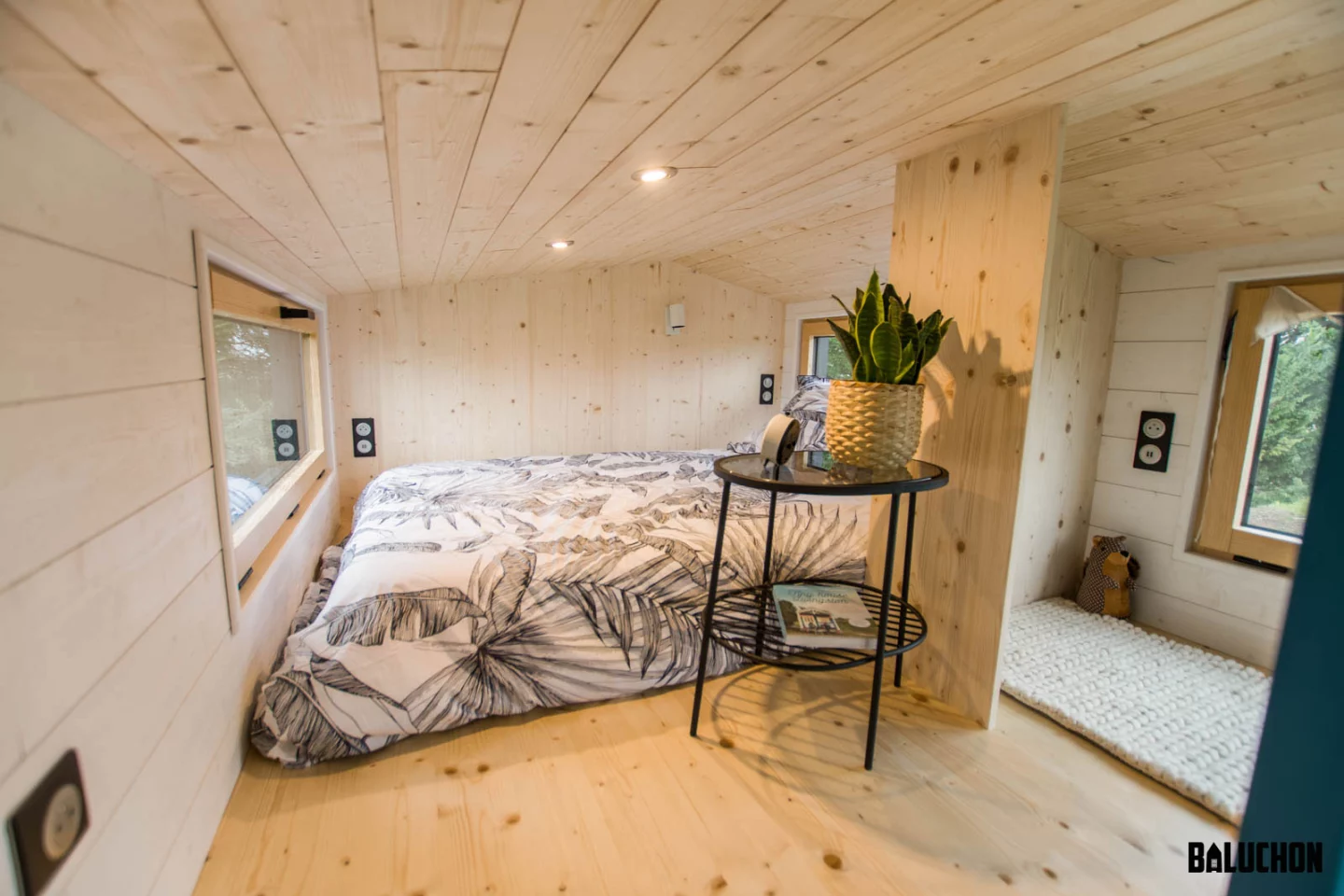 The Kejadenn's main bedroom is situated in the upstairs loft area and is a typical tiny house-style space with a low ceiling and a double bed