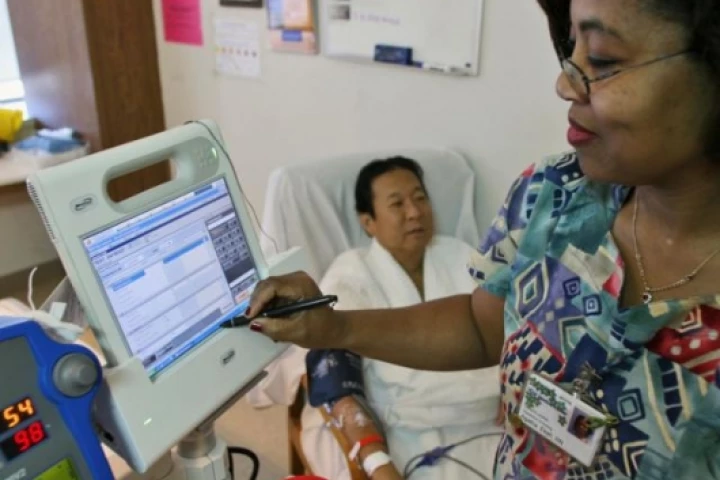 Nurse Agatha Ekeh, right, updates patient Charles Khim's medical record using Motion Computing's C5, the first product based on Intel's mobile clinical assistant platform, Tuesday, Feb. 20, 2007, at UCSF Medical Center in San Francisco.