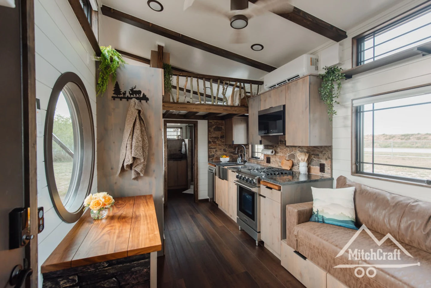 Rustic tiny house has a spacious interior and a balcony up top
