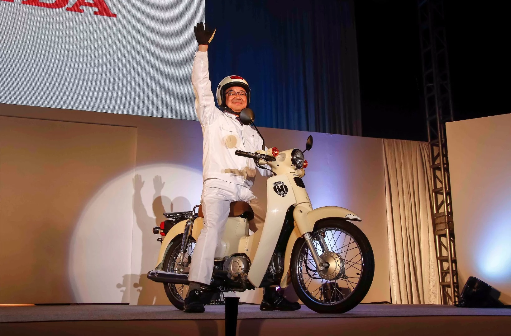 Takahiro Hachigo, Honda CEO, rides on stage aboard a 2018 Honda Super Cub, during a special celebration at the Kumamoto factory