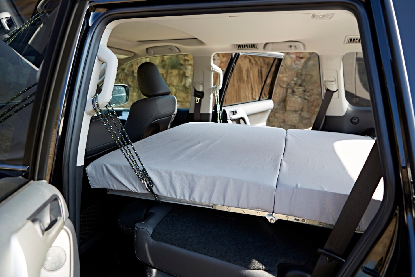 The fold-out bed is supported by straps around the grab handles