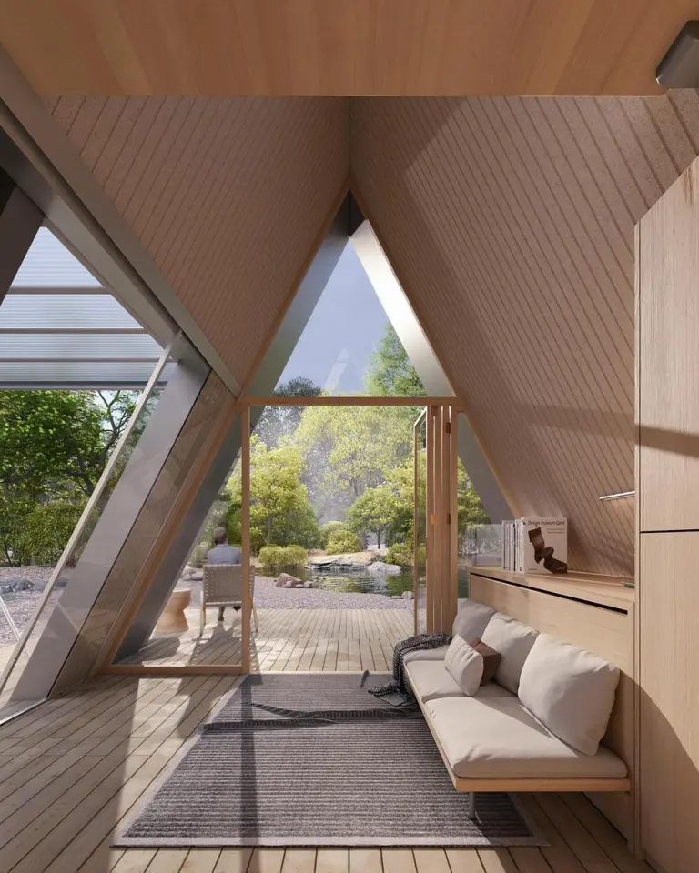 The timber-lined interior opens onto an outdoor deck through a large triangular glazed entrance
