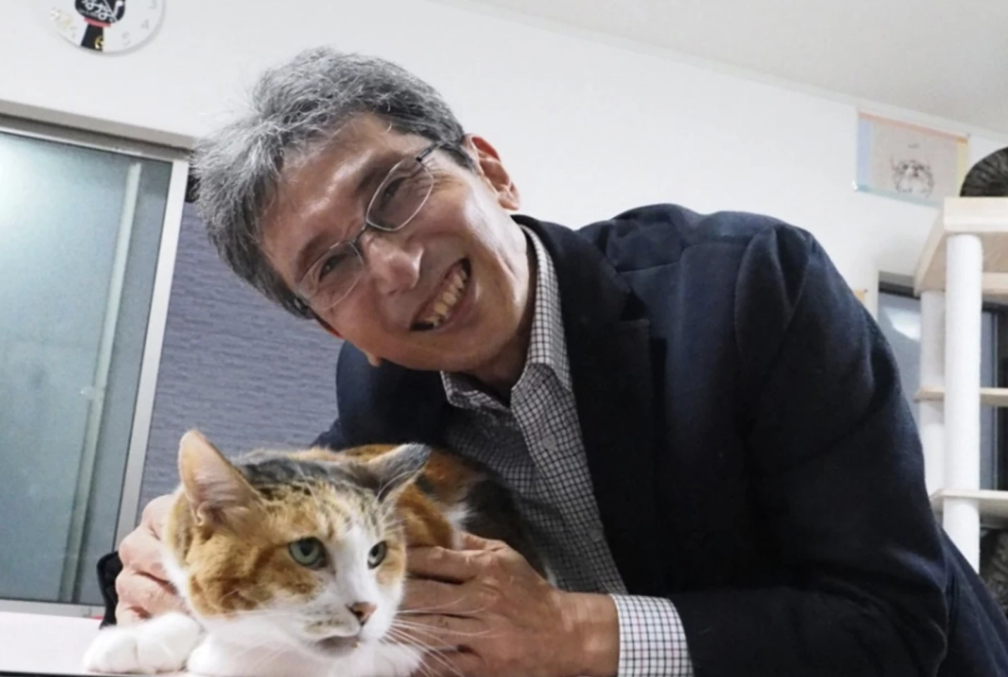 Professor Hiroyuki Sasaki, a geneticist at Kyushu University, makes friends with one of the calico cats at a local shelter during his research