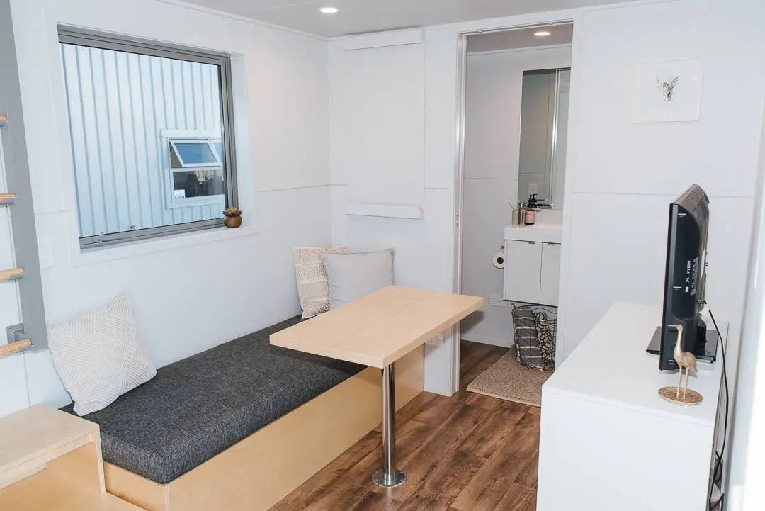The Larissa and Tyler Tiny House's living room includes a removable table that's stowed on a mount on the wall