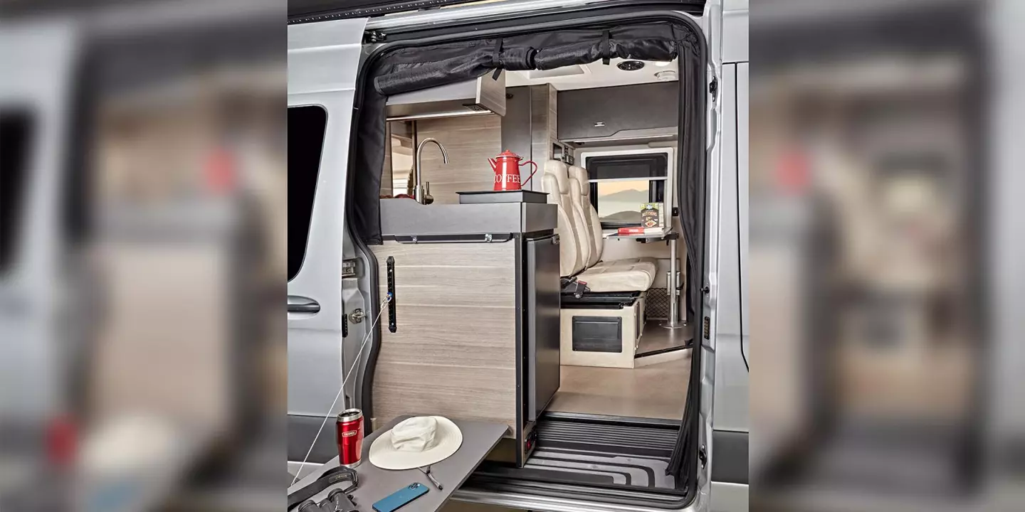 The indoor/outdoor kitchen space includes a portable induction cooktop, drop-down outdoor table and easily accessible end fridge
