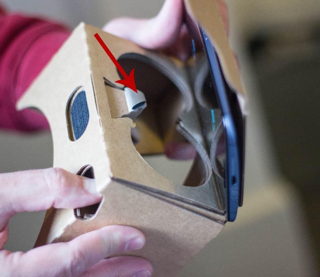 The arrow indicates a lever, activated by pressing the button (shown), which serves as an action button in Cardboard content