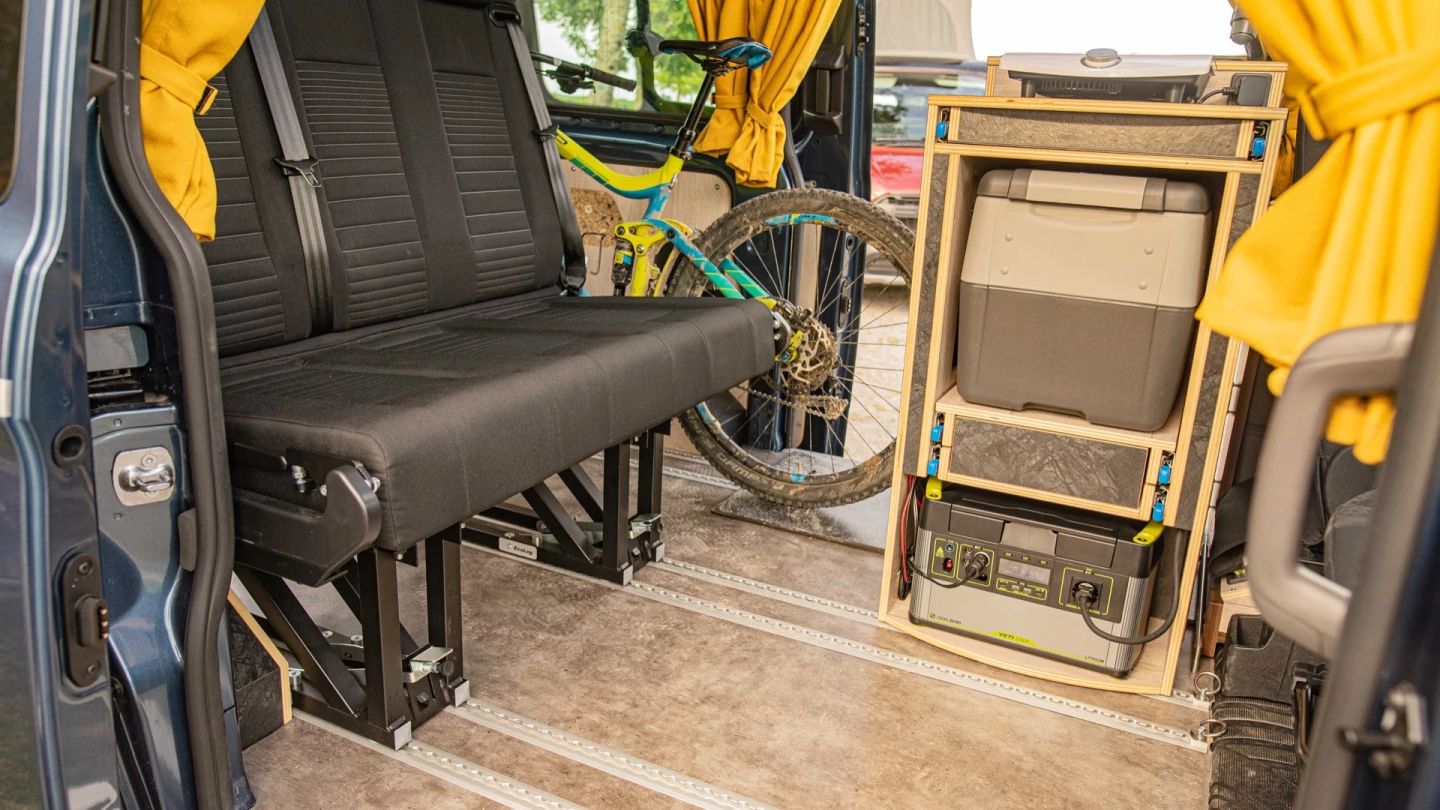 The Allrounder kitchen's induction cooktop hooks up to the included Goal Zero power station (note that the kitchen is rotated here to accommodate the mountain bike and can spin so the fridge faces rearward to clear the floor rails and move the bench up)
