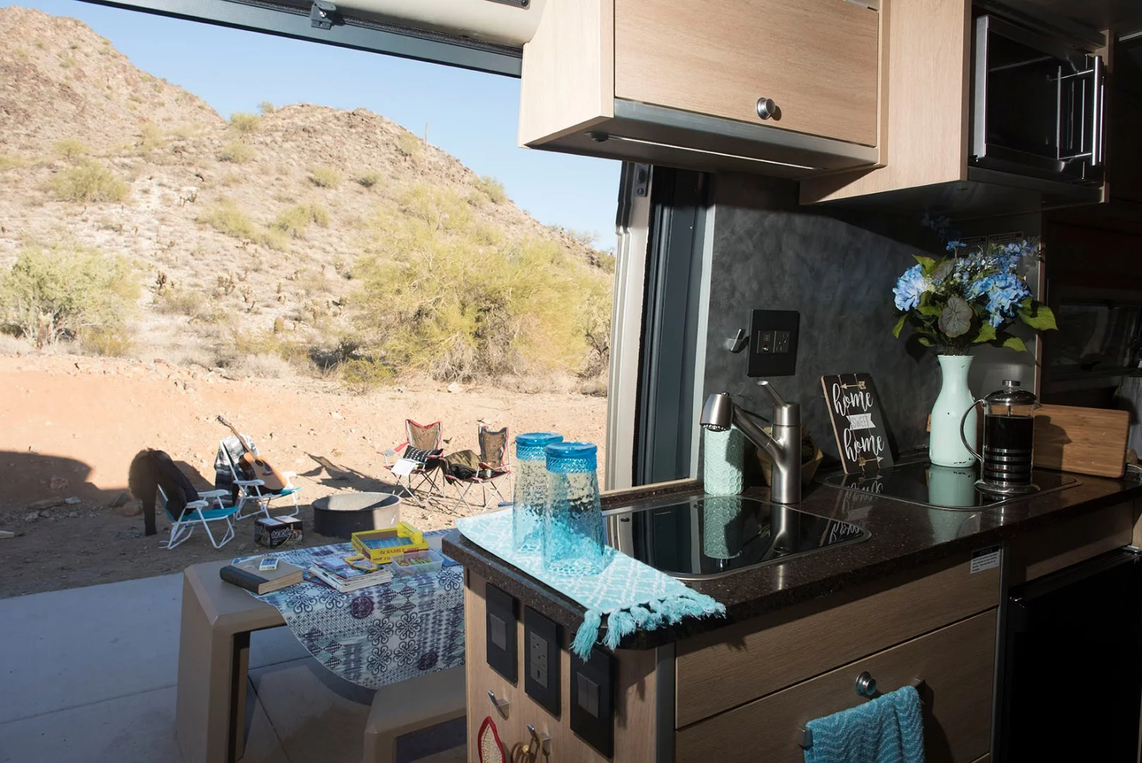 The kitchen area includes a dual-burner stove, sink, microwave and fridge