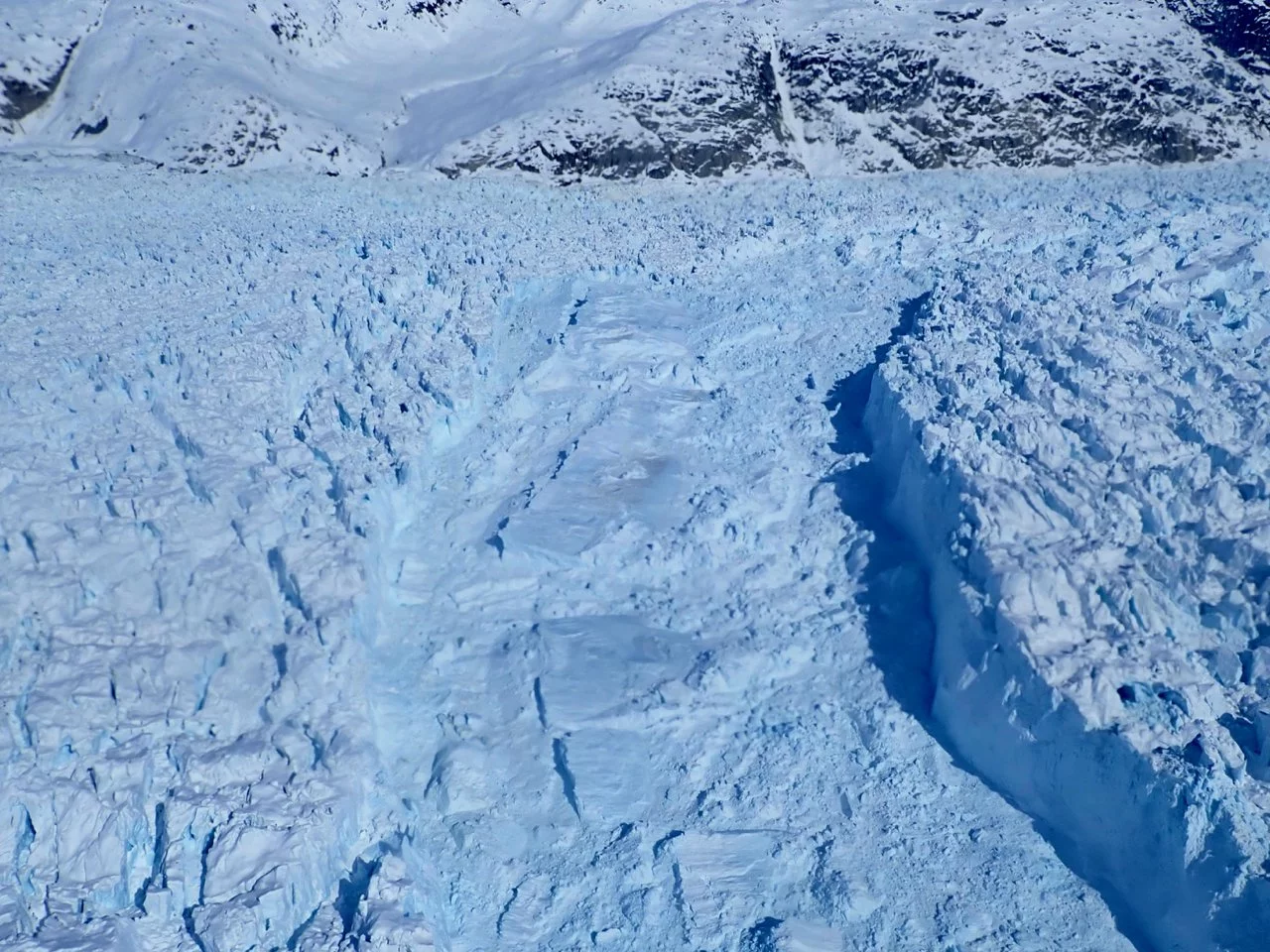 Arctic flight in April 2018, Helheim Glacier (left) recently calved a large iceberg (right) that has not capsized or overturned yet