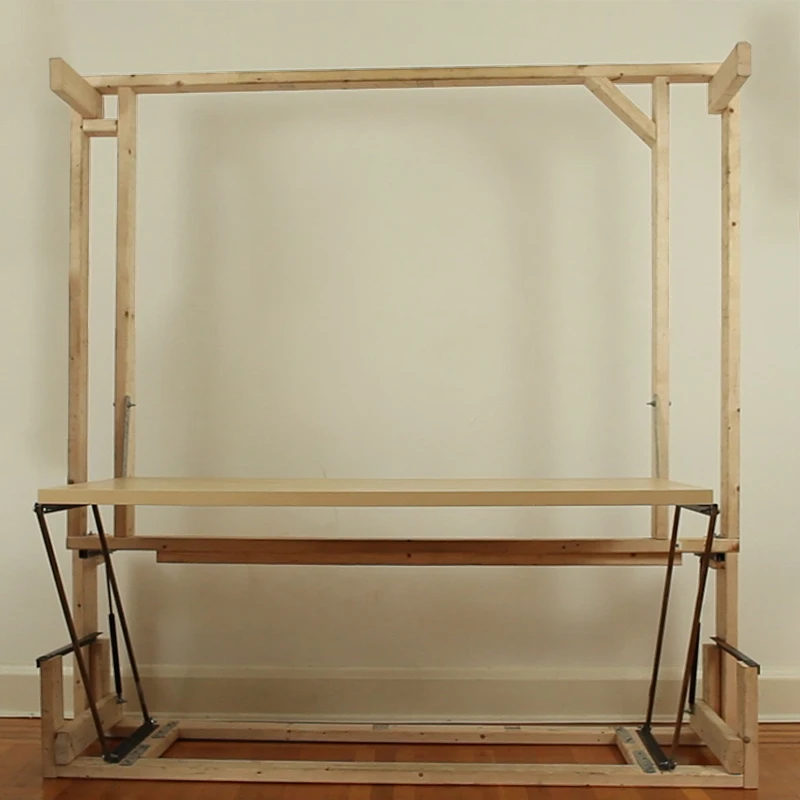 The wooden frame rests against a wall, lifting up the full-size desk in the process