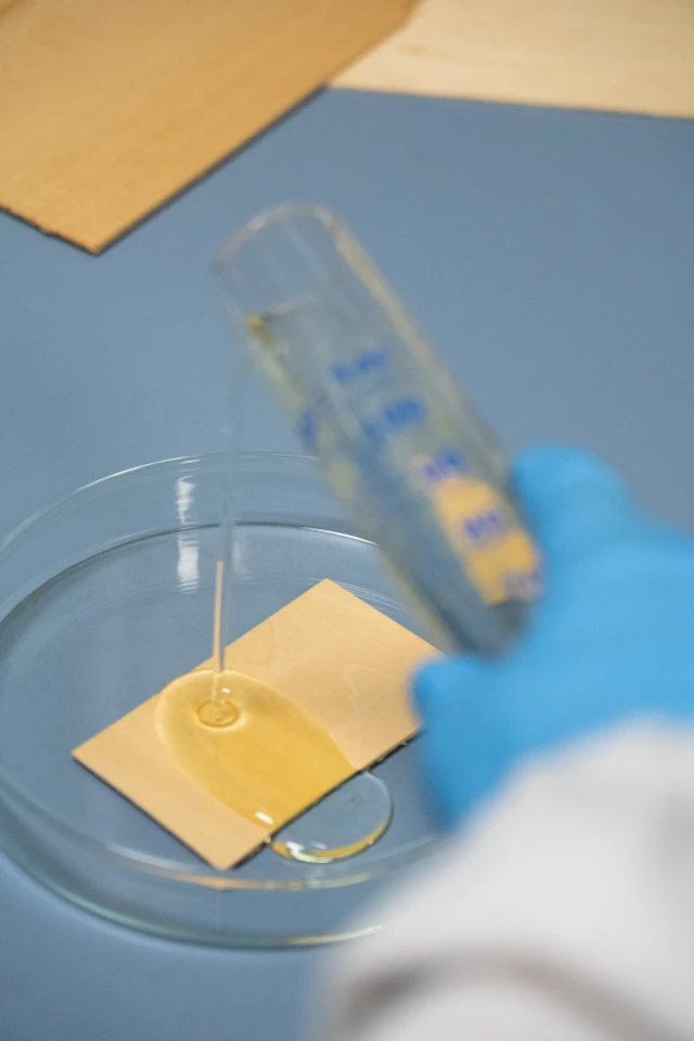 A Cyrene solution is added to a wood sheet in the lab