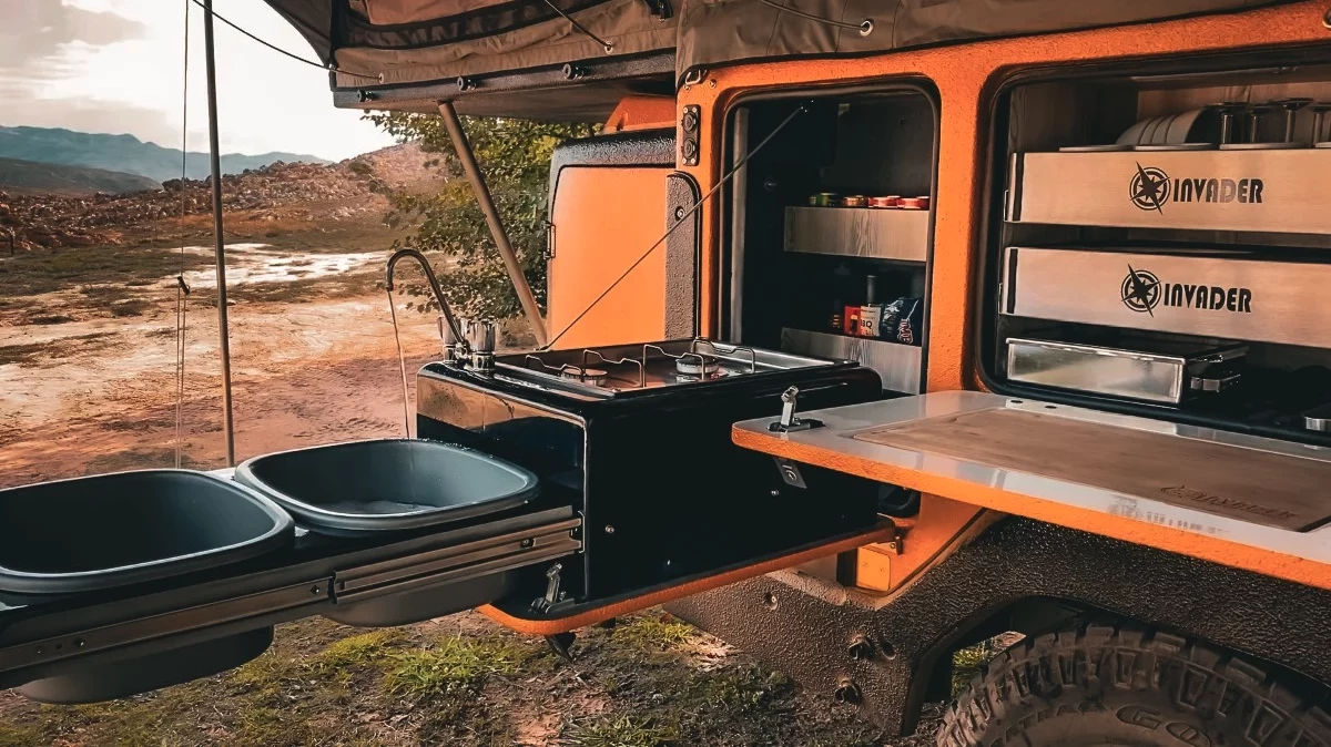 The stove unit folds down out of the cabinet, and the removable sink basins set up on the slide