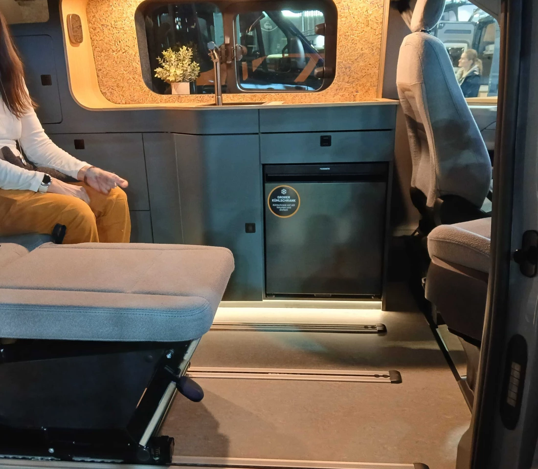 Inside the Ultimate camper van with one rear seat folded into sleeper form and the other left in sitting form