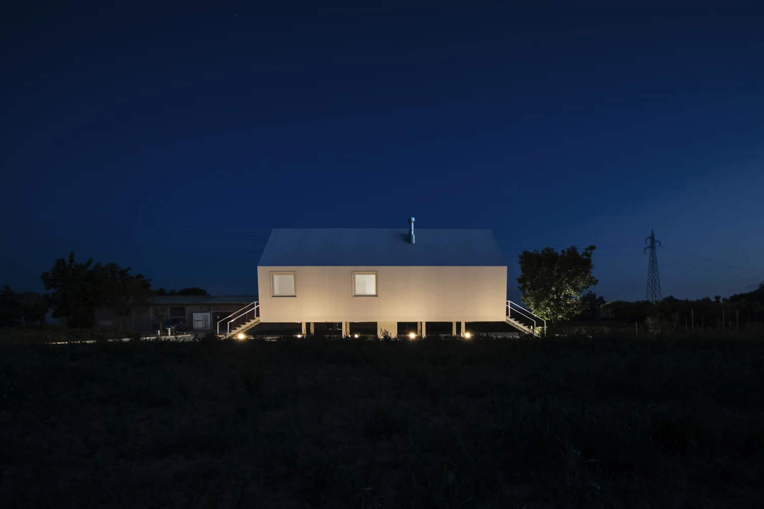 The home is elevated above the ground and is supported by a series of short steel pillars