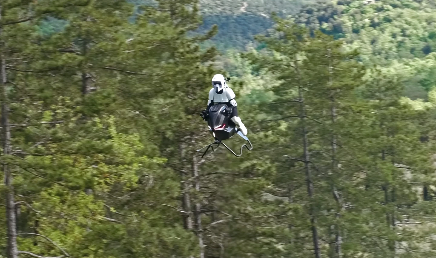 The Volonaut Airbike, Stormtrooper astride, flying above the trees